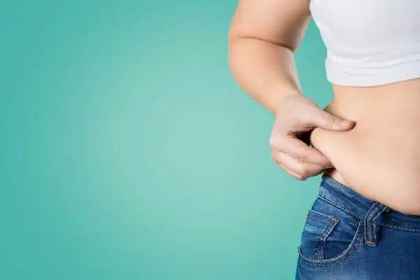 Image of woman pinching her love handles to show weight gain Virginia Water